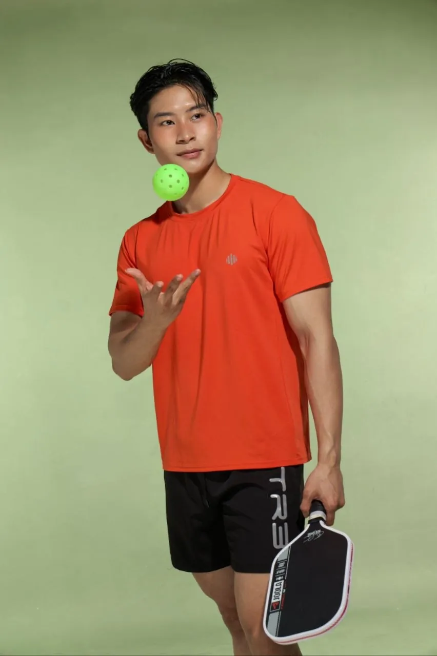 Người mẫu mặc áo thể thao TR3 DAILY màu cam cầm vợt pickleball